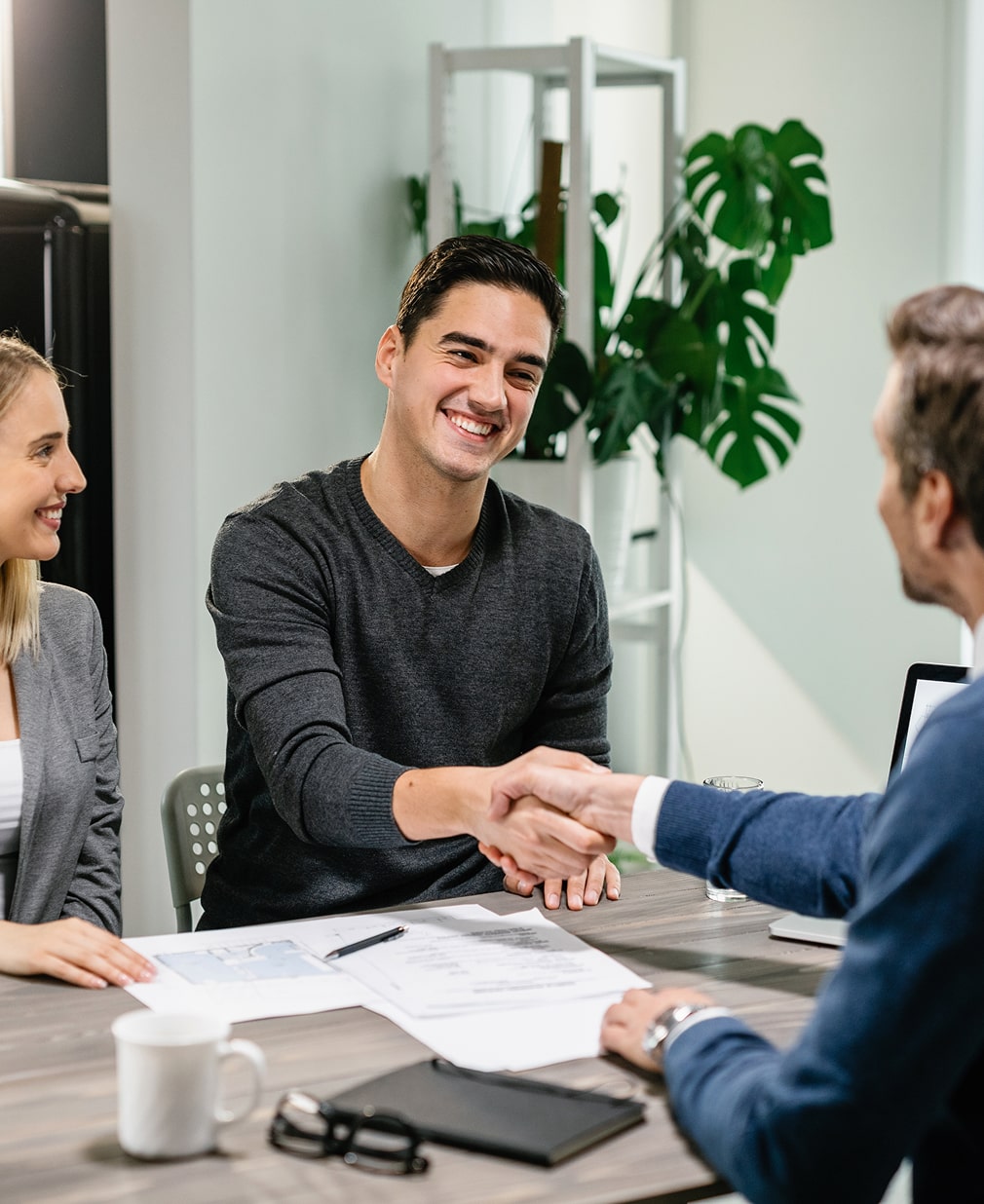 young happy couple making agreement with their financial advisor home men are shaking hands min